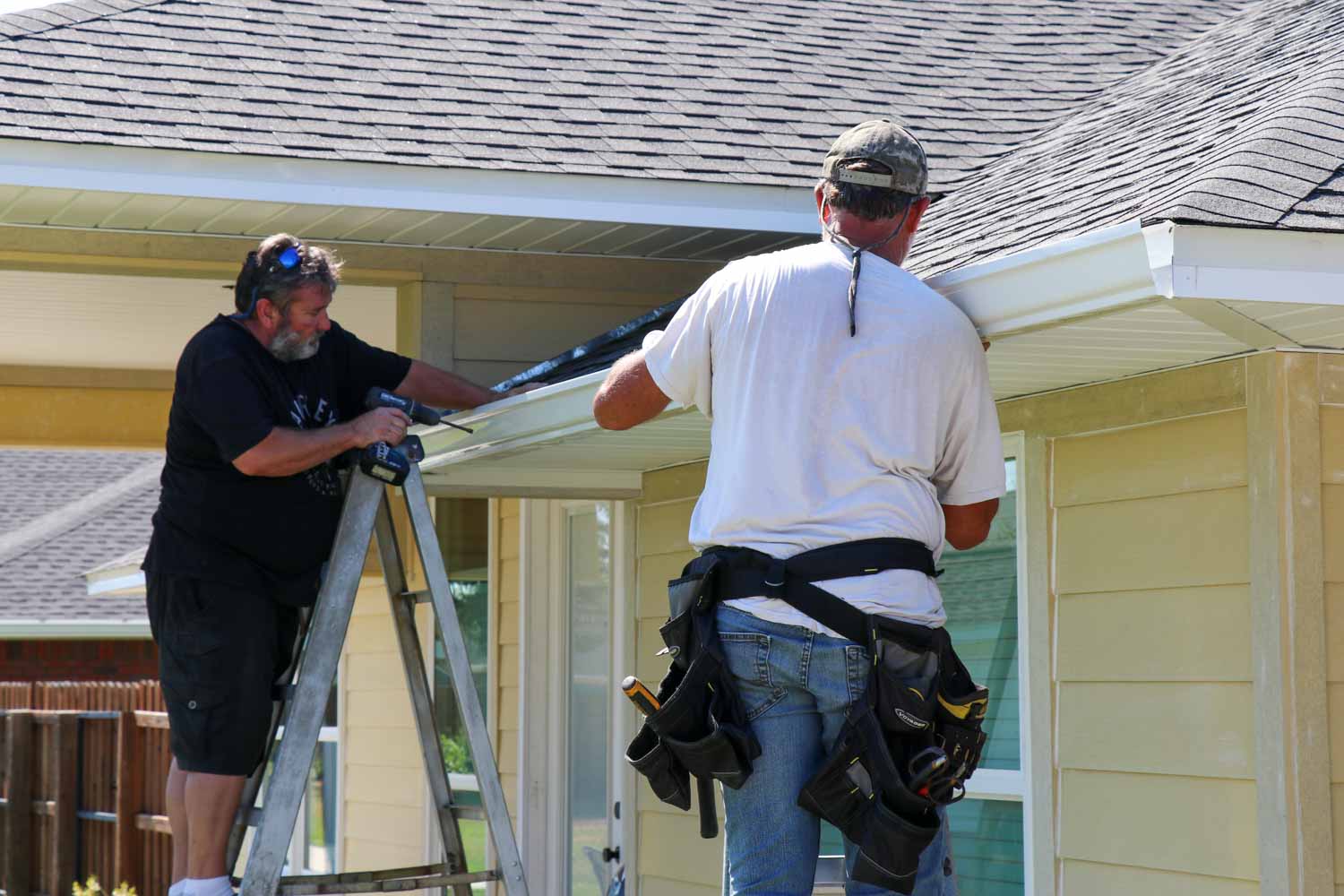 Gordon and Larry installing a length of seamless gutter on a home in Panama City, FL