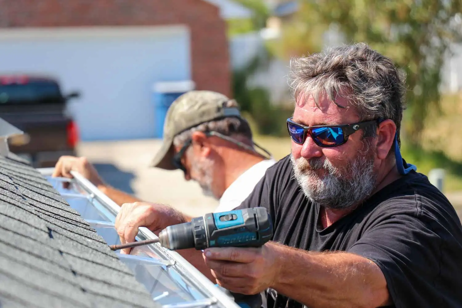 Seamless rain gutters being installed on a roof.